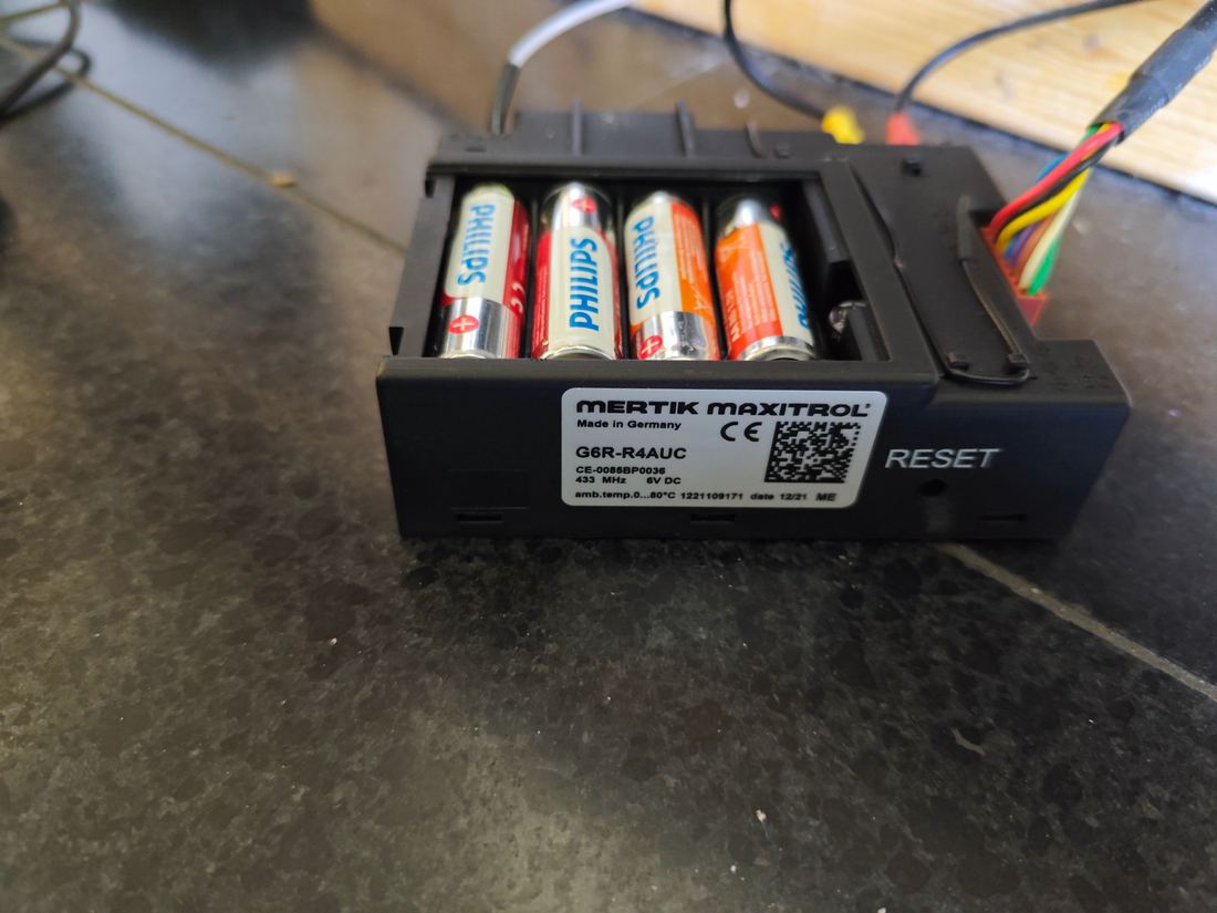 Ontvanger van een gashaard met geopend batterijvak, vier AA-batterijen zichtbaar
